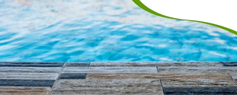 A close-up of paving around a pool area, showing textured tiles leading to blue water.