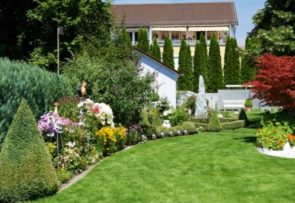 A green lawn and flower beds show designing your garden creatively.