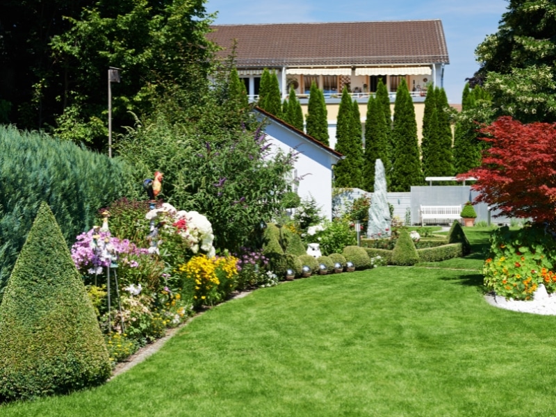 A green lawn and flower beds show designing your garden creatively.