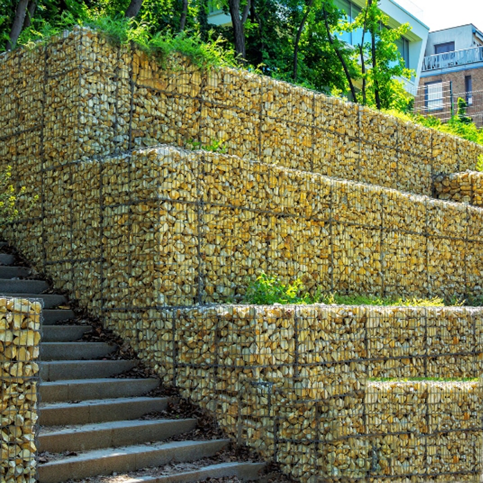 Retaining Walls Sydney: Stone retaining wall with stairs and landscaping, showcasing professional installation.