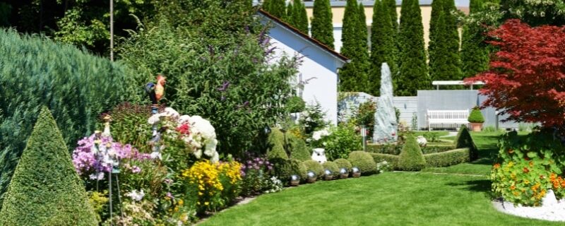 A green lawn and flower beds show designing your garden creatively.
